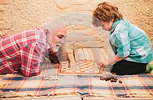 Little boy playing chess with his Grandfather. Chess hobbies - granddad with grandson on a playing chess.
