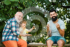 Little boy playing chess with his Grandfather and Father. Cute boy developing chess strategy. Family holiday and