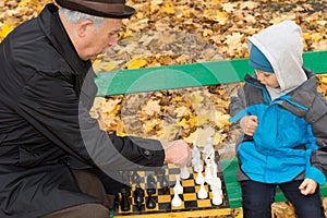 Little boy playing chess with his Grandpa