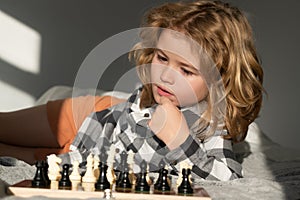 Little boy are playing chess at home. Clever concentrated and thinking child playing chess. Child boy developing chess