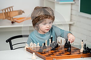 Little boy playing chess. Pupil kid thinking about his next move in a game of chess. Intelligent kids.