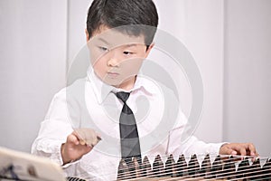 little boy playing the Chinese zither