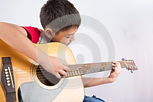 Little boy playing classic guitar course on white background