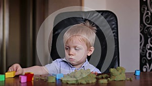 Little boy playing with colored sand at home.