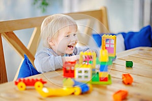 Little boy playing with colorful plastic blocks at kindergarten or at home