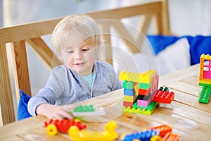 Little boy playing with colorful plastic blocks at kindergarten or at home