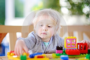 Little boy playing with colorful plastic blocks at kindergarten.