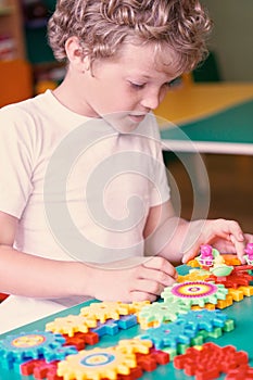 Little boy playing with colorful plastic bricks at the table. Toddler having fun and building out of bright constructor