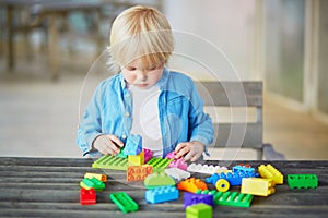 Little boy playing with colorful plastic construction blocks