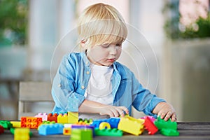 Little boy playing with colorful plastic construction blocks