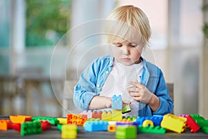 Little boy playing with colorful plastic construction blocks