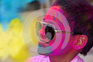 Little boy playing with colors, Wearing glasses in school uniform, Concept for Indian festival Holi