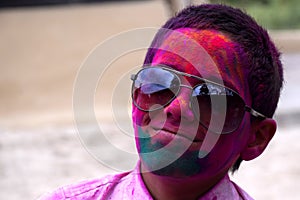 Little boy playing with colors, Wearing glasses in school uniform, Concept for Indian festival Holi