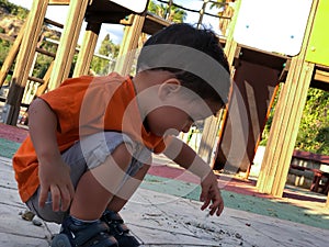 Little boy playing with dirt in a playground