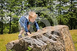 Little boy playing in a field near the big stones