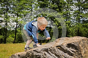 Little boy playing in a field near the big stones