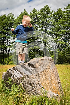 Little boy playing in a field near the big stones