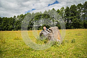 Little boy playing in a field near the big stones