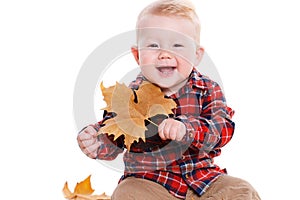 Little boy playing on the floor with maple leaves.