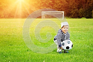 Little boy playing football on the field with gates