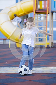 Little boy playing football soccer on the field