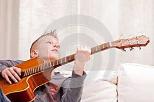 Little boy playing guitar at home