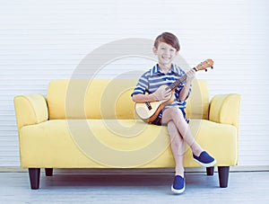 A little boy is playing guitar in living room