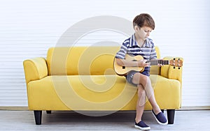 A little boy is playing guitar in living room