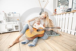 Little boy playing on guitar with mom