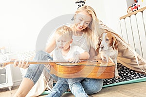 Little boy playing on guitar with mom