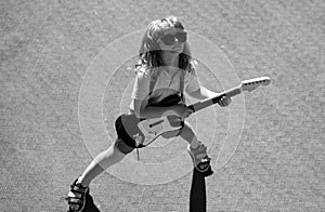 Little boy playing guitar outdoor. Music for children. Funny little hipster musician child playing guitar.
