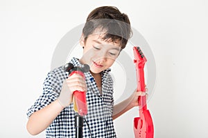 Little boy playing guitar and sing with microphone