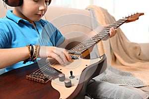 Little boy playing guitar on sofa