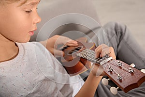 Little boy playing guitar on sofa in room