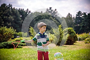 Little boy playing with his soap bubbles toy in the park. Child activity. Springtime concept