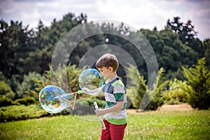 Little boy playing with his soap bubbles toy in the park. Child activity. Springtime concept