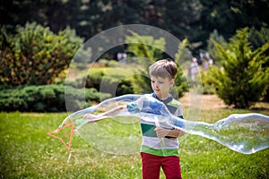 Little boy playing with his soap bubbles toy in the park. Child activity. Springtime concept