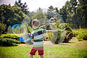 Little boy playing with his soap bubbles toy in the park. Child activity. Springtime concept