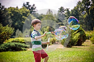 Little boy playing with his soap bubbles toy in the park. Child activity. Springtime concept