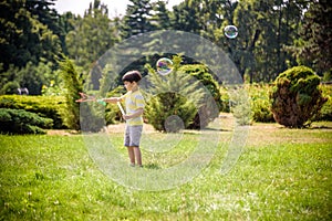 Little boy playing with his soap bubbles toy in the park. Child activity. Springtime concept