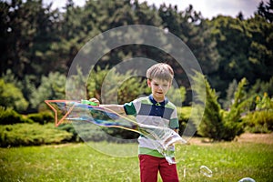 Little boy playing with his soap bubbles toy in the park. Child activity. Springtime concept