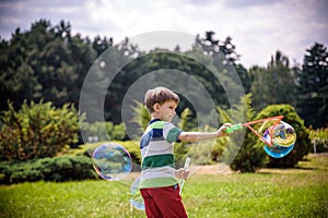 Little boy playing with his soap bubbles toy in the park. Child activity. Springtime concept