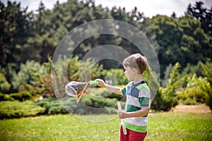 Little boy playing with his soap bubbles toy in the park. Child activity. Springtime concept