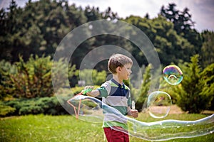 Little boy playing with his soap bubbles toy in the park. Child activity. Springtime concept