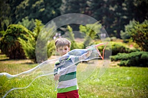 Little boy playing with his soap bubbles toy in the park. Child activity. Springtime concept