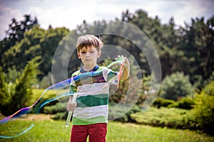 Little boy playing with his soap bubbles toy in the park. Child activity. Springtime concept