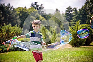 Little boy playing with his soap bubbles toy in the park. Child activity. Springtime concept