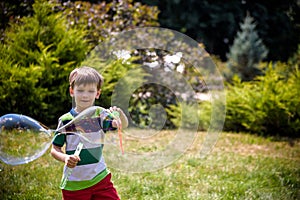 Little boy playing with his soap bubbles toy in the park. Child activity. Springtime concept