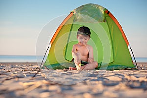 Pequeno chico en su una carpa sobre el Playa 