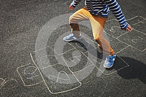 Little boy playing hopscotch on playground